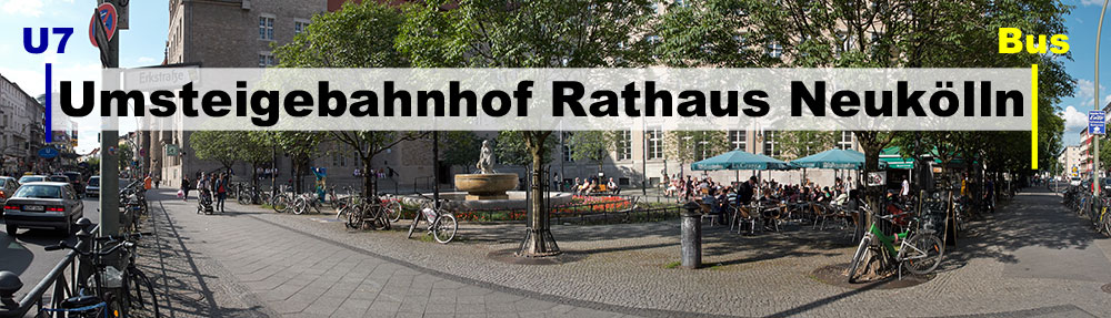 Panoramafoto: Weg von der Bushaltestelle zum U-Bahn-Eingang mit Textbanderole -Umsteigebahnhof Rathaus Neukölln-.